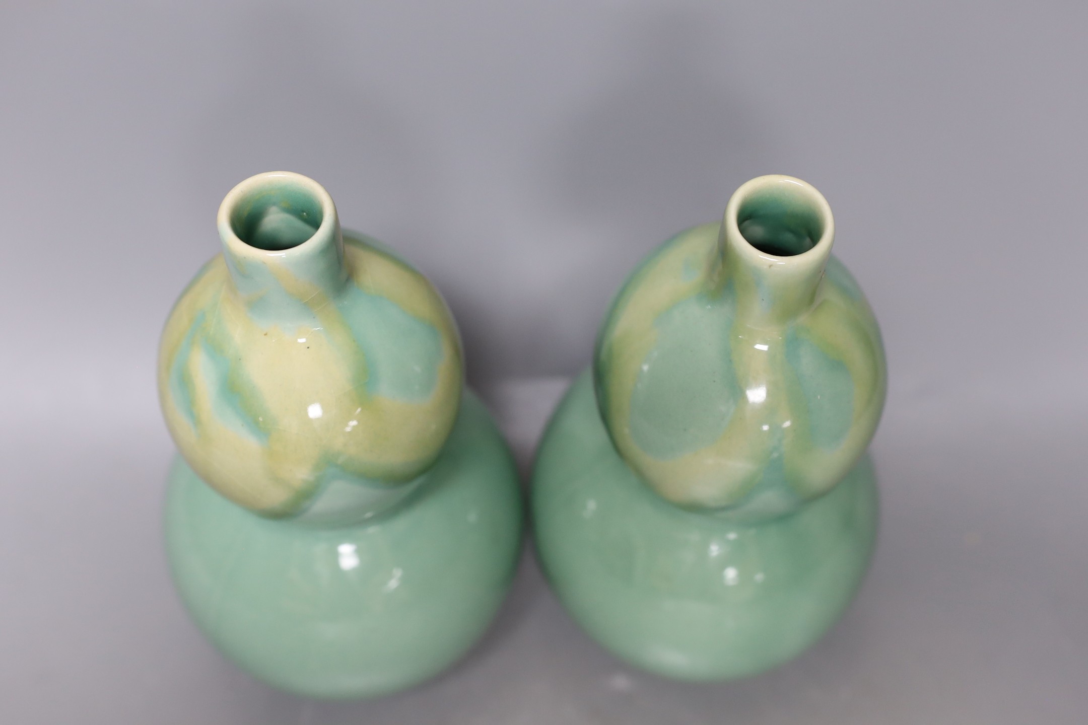 A pair of Chinese celadon ground bottle vases 21cm tall